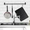 A kitchen sink area with a drying mat and a pan hanging from a rack. Produktbild-Vorschau