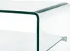 A close-up view of a transparent glass coffee table, showing the curved edge and a shelf. Podgląd zdjęcia produktu