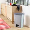 A light gray pedal bin is placed on a wooden floor next to a wooden cabinet. Náhled obrázku produktu