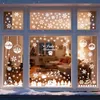 Christmas-themed window decorations applied to a window, showing a festive scene with snowflakes, trees, and ornaments. Produktbild-Vorschau