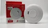 A smoke detector and its packaging are displayed on a white and gray background. Produktbild-Vorschau