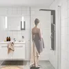 A woman wrapped in a towel stands in a modern bathroom, facing a black shower panel. Náhľad obrázku produktu
