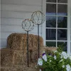 Two LED-decorated spheres on poles are placed in front of hay bales and flowers, next to a white-paneled wall and a window. Produktbild-Vorschau