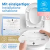A person is holding an installation template over a toilet seat, with other installation guides and product information visible. Produktbild-Vorschau