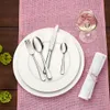A table setting with cutlery, plates, and a wine glass on a pink placemat. Náhled obrázku produktu
