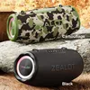 Two ZEALOT S87 BT speakers, one in camouflage and one in black, are displayed on rocks and grass. Produktbild-Vorschau