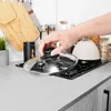 A hand is placing a glass lid on a gas stove. Podgląd zdjęcia produktu