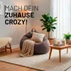 A cozy living room scene with a large beanbag chair, a small wooden table, plants, and a rug. Voir les images du produit
