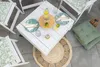 An outdoor table setting with white wooden chairs and a white pallet coffee table, decorated with green leaf-patterned cushions and plates, and a carafe of lemon water. Anteprima dell’immagine prodotto