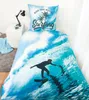 A bed with a duvet cover and pillow featuring a surfing theme. Produktbild-Vorschau