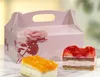 A pink cake box with a rose design and two slices of cake in front of it. Anteprima dell’immagine prodotto