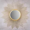 A gold sunburst mirror against a textured gray background. Produktbild-Vorschau