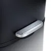 A close-up view of the pedal mechanism on a black trash can. Produktbild-Vorschau