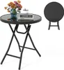 A round folding table with a glass top, set up and decorated with a vase of flowers and books. A second, folded table is shown in the background. Produktbild-Vorschau