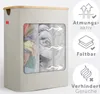 A beige laundry basket with a wooden lid and a window showing laundry inside, with marketing icons and text on the right side. Produktbild-Vorschau
