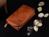 A brown leather wallet is displayed on a black surface, with decorative stones and a bracelet nearby. Náhľad obrázku produktu