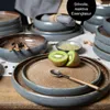 A table setting with plates, bowls, cutlery, and kiwi fruit, suggesting a meal or dining experience. Produktbild-Vorschau