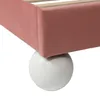 A close-up of the corner of a pink upholstered bed frame with a white spherical leg. Anteprima dell’immagine prodotto