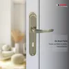 A close-up of a bronze door handle on a white door, with a blurred background of a room interior. Produktbild-Vorschau