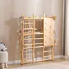 A wooden indoor climbing frame with various attachments like a climbing wall, swing, and rope net, set up in a room with a light-colored wall and floor. Produktbild-Vorschau
