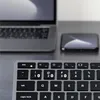 A close-up view of a Satechi Slim X1 wireless keyboard, with a laptop and a smartphone in the background. Náhled obrázku produktu