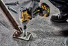 A person is using a DeWALT impact wrench to attach a metal plate to a concrete surface. Podgląd zdjęcia produktu
