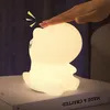A hand touching a glowing silicone dinosaur night light on a book. Voir les images du produit