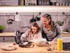 A woman and a girl are in a kitchen making waffles. Náhled obrázku produktu