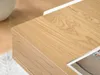 A close-up view of a wooden desk with a white edge, showing the wood grain. Voir les images du produit