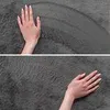 Two close-up shots of a person's hands touching a soft, gray, textured surface, likely a rug. Podgląd zdjęcia produktu
