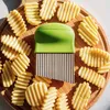 A green and silver potato cutter is placed on a wooden board surrounded by crinkle-cut potato slices. Produktbild-Vorschau