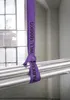 A purple lifting sling with text is holding several silver metal pipes. Produktbild-Vorschau
