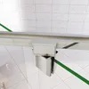 A close-up view of a shower door hinge and track system, set against a tiled wall and floor. Produktbild-Vorschau