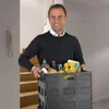 A man is holding a black foldable shopping trolley filled with groceries in a hallway with stairs. Anteprima dell’immagine prodotto