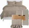 A taupe duvet cover and pillowcases with ruffles are displayed on a bed, with packaged pillowcases in the foreground. Produktbild-Vorschau