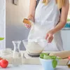 A person is adding spices to flour in a bowl, preparing to make dough. Voir les images du produit