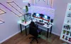 A modern gaming desk setup with dual monitors, a computer tower, and LED lighting. Produktbild-Vorschau