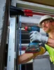 A construction worker is using a Bosch impact driver to install a window frame. Náhľad obrázku produktu