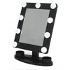 A black makeup mirror with LED lights and two small holders on its base, set against a white background. Produktbild-Vorschau