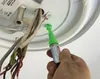 A hand is holding a green spray marker and applying it to electrical wires connected to a ceiling fixture. Náhľad obrázku produktu