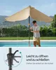 A man is opening a beige patio umbrella next to a swimming pool. Produktbild-Vorschau
