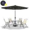 A dark gray patio umbrella with LED lights, a glass-topped table, and four beige folding chairs are arranged on a white background. Produktbild-Vorschau