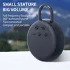 A black portable speaker is shown in front of a blurred background of mountains and sky. Produktbild-Vorschau