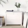 A white wooden chest sits next to a bed, with books and a vase of greenery on top. A woven basket with blankets is to the left. Náhľad obrázku produktu
