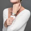 A woman wearing a white sweater and jewelry, including a watch and rings. Náhled obrázku produktu