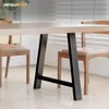 A close-up view of a dining table with black metal legs and wooden chairs with tan cushions. Podgląd zdjęcia produktu