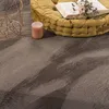 A close-up view of a fluffy rug with a yellow cushion and a pink candle. Produktbild-Vorschau