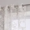 Close-up of a sheer curtain with a baroque-style pattern hanging from a curtain rod. Produktbild-Vorschau