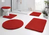 A bathroom setting with a toilet and several red bath mats. Produktbild-Vorschau