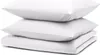 A stack of white bedding items, including pillows and a folded duvet or comforter, against a white background.